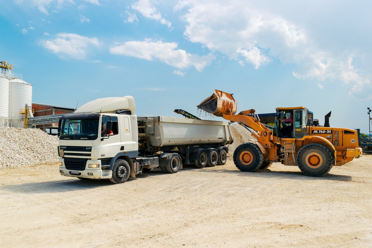 excavator putting sand in truck